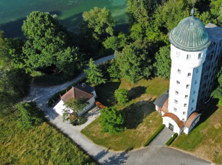 Luftaufnahme der Eventlocation am Ufer des Seerheins. Im Vordergrund das historische Pumpenhaus mit Terrasse, umgeben von einem Garten. Rechts der hohe, weiße Wasserturm mit grünem Kuppeldach. Im Hintergrund der Fluss und dichte Bäume.